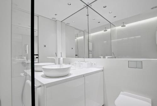 a white bathroom with two sinks and a mirror at Andersia Park in Poznań