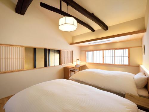 deux lits dans une chambre avec deux fenêtres dans l'établissement Kyo no Ondokoro Gokomachi Ebisugawa #3, à Kyoto