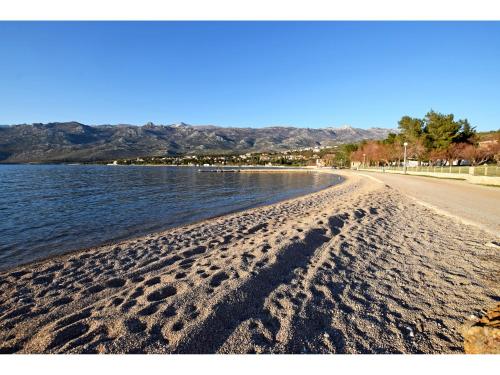a beach with footprints in the sand and water at APARTMAN DANE in Rovanjska