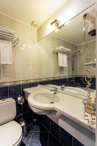 a bathroom with a sink and a toilet and a mirror at Ambassador in Almaty