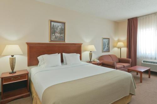a hotel room with a large bed and a chair at Baymont by Wyndham Portage in Portage