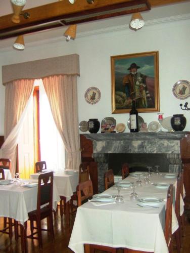 a dining room with white tables and a painting on the wall at Alentejano Low Cost Hotel in Estremoz