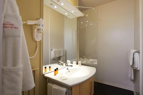 a bathroom with a sink and a shower with a mirror at Grand Hotel in Dax