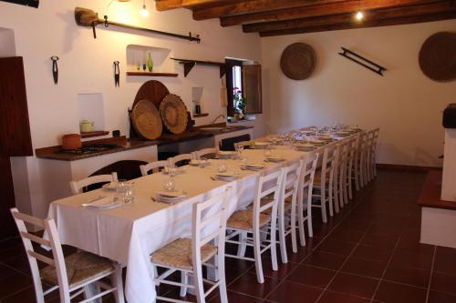 a long table with white tables and chairs in a room at Agriturismo Cuile de Molino in Porto Torres