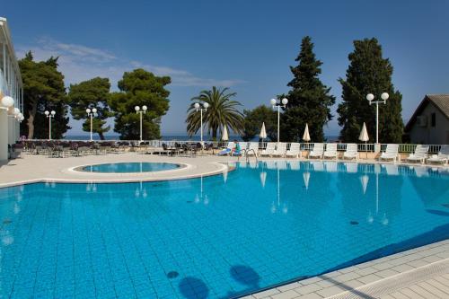 una gran piscina azul con mesas y sillas en Hotel Faraon en Trpanj