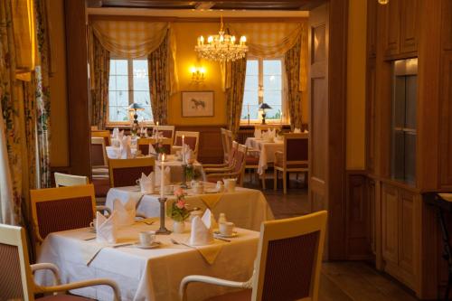 un restaurant avec des tables et des chaises blanches et un lustre dans l'établissement Herrenhaus von Löw, à Bad Nauheim