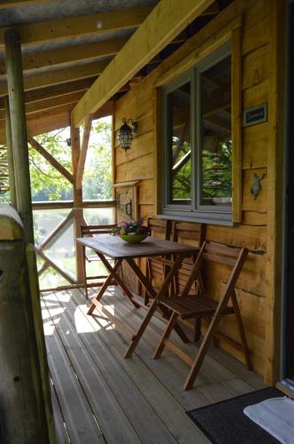 einen Tisch und Stühle auf der Veranda einer Hütte in der Unterkunft LES GITES INSOLITES DE LA CASCADE in Lespesses