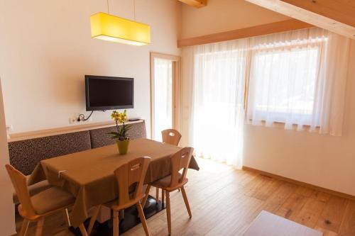 a dining room with a table and chairs and a television at Residence Armonia in Colfosco