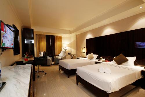 a hotel room with two beds and a flat screen tv at Hotel Park Residency in Nilambūr