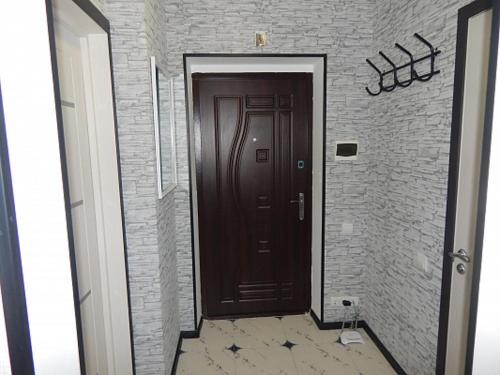 pasillo con puerta marrón y pared de ladrillo en Ukrainska Apartment, en Irpín