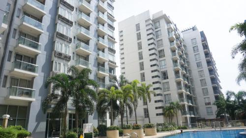 two tall buildings with palm trees in front of a pool at Palm Tree Condos across NAIA3 by Beth in Manila