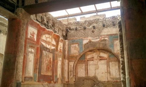 a room with paintings on the walls of a building at Villa Cua in Ercolano
