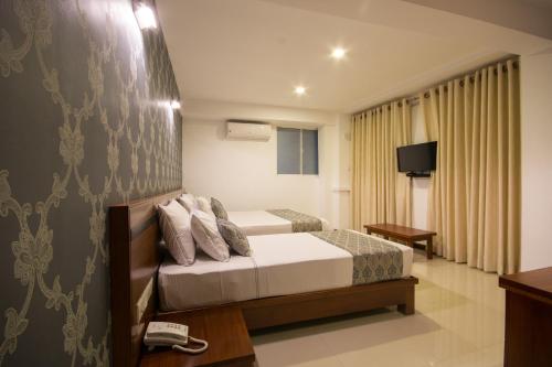 a hotel room with a bed and a television at Ceyloni City Hotel in Kandy