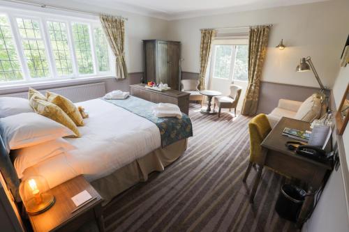 a hotel room with a large bed and a desk at The Stanneylands in Wilmslow