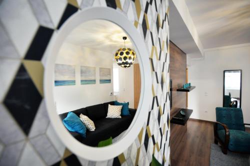 a living room with a black couch and a mirror at ONE Luxury Suites Eger in Eger