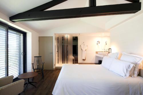 a bedroom with a large white bed and a bathroom at Auberge Du Paradis in Saint-Amour-Bellevue