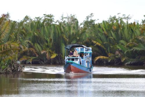 a boat on a river with people on it at Orangutan Houseboat Park Tanjung Puting in Pangkalan Bun