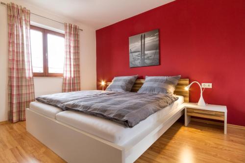 a bedroom with a red wall and a bed at Ferienwohnungen Alpentraum - freiSicht in Fischen