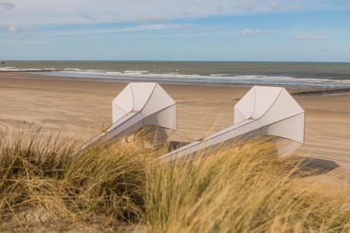 two white objects sitting on a beach near the ocean at Apparthotel De Wielingen in Westende Bad
