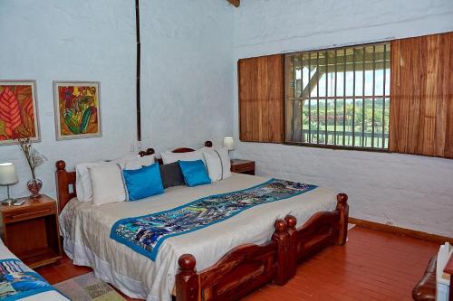 a bedroom with a bed with blue pillows and a window at Finca Hotel La Negrita in Montenegro