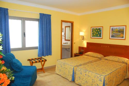 a bedroom with a bed and a blue chair at Hotel Pujol in Las Palmas de Gran Canaria