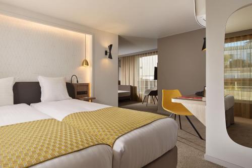 パリにあるオートゥイユ トゥール エッフェルのベッドとデスクが備わるホテルルームです。