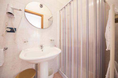 a white bathroom with a sink and a mirror at Hotel Elefante Bianco in Crespellano