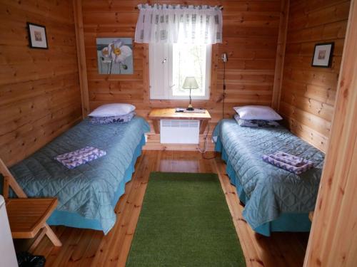 two beds in a log cabin with a window at Guesthouse Miekkala in Lappeenranta