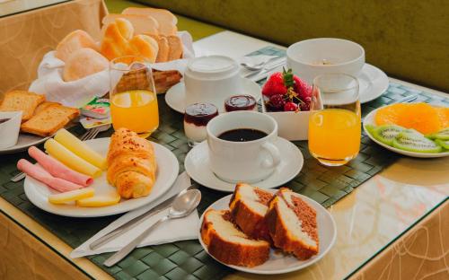 a breakfast table with plates of breakfast foods and orange juice at Hotel Império do Rei in Castelo Branco