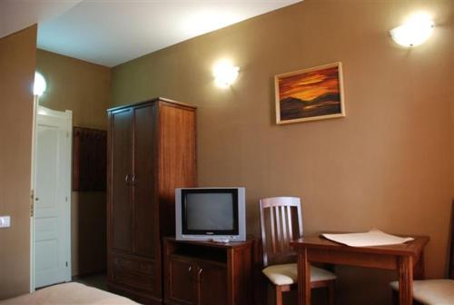 um quarto com uma secretária, uma televisão e uma mesa com uma cadeira. em Borsika panzió em Ciumani