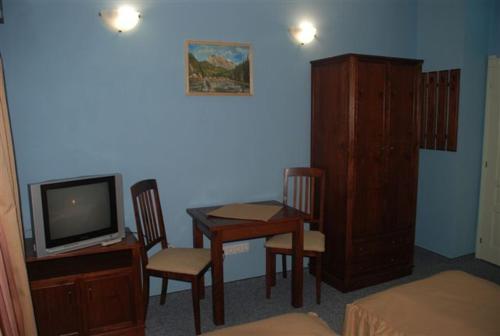 una camera con tavolo, TV, tavolo e sedie di Borsika panzió a Ciumani