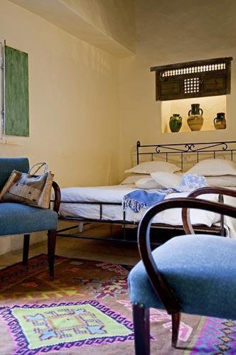 a bedroom with a bed and two chairs and a rug at Hotel Dar Dhiafa in Houmt Souk