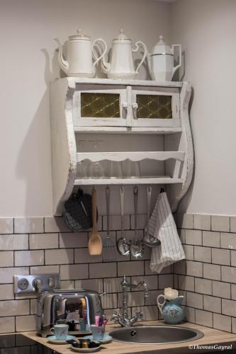 a kitchen with a sink and a shelf with pots and pans at Demeure Terrisse La Maison in Marseillan