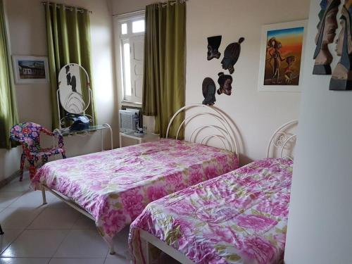 1 dormitorio con 2 camas y una ventana con cortinas verdes en Maravilhosa casa de praia, en Aracaju
