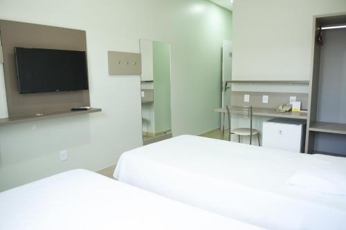 a white room with two beds and a tv at Uiramutam Palace Hotel in Boa Vista