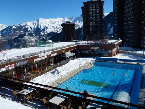 una piscina en la parte superior de un edificio con montañas cubiertas de nieve en Au pied des pistes (Le Corbier/73) en Villarembert