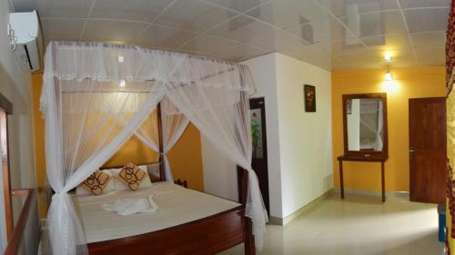 a bedroom with a bed with a canopy at Palitha Homestay in Sigiriya