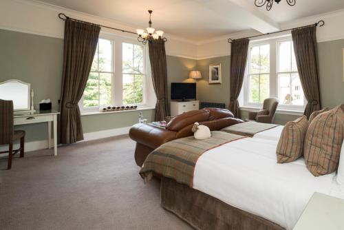 a bedroom with a large bed with a couch and chairs at Three Ways House Hotel in Chipping Campden