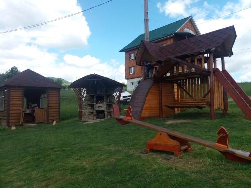 a log cabin with a slide and a playground at Сонячний Котедж in Slavske