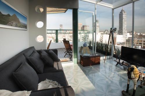 a living room with a couch and large windows at Dúplex/terraza privada en corazón Centro Histórico in Mexico City