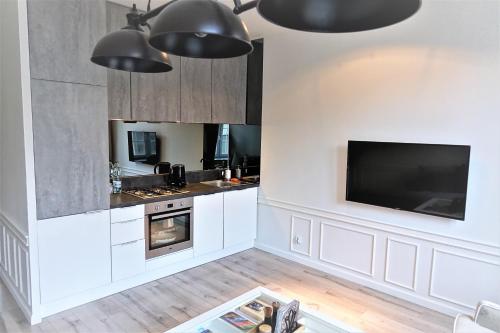 a kitchen with white cabinets and a flat screen tv at Tkacka Home in Gdańsk