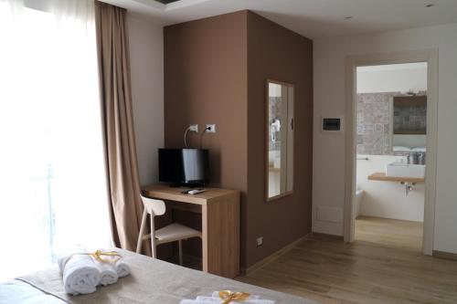 1 dormitorio con 1 cama y escritorio con TV en Musmelia Rooms - Affittacamere, en Mussomeli