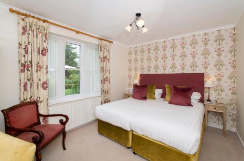 a bedroom with a bed and a chair and a window at Three Ways House Hotel in Chipping Campden