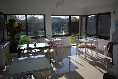 Habitación con mesas, sillas y ventanas. en Pensiunea Casa Zece, en Turda