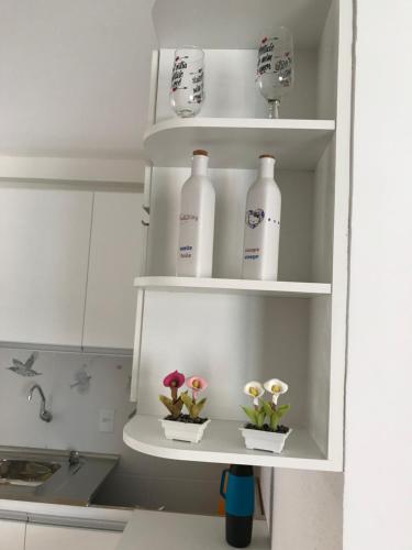 a kitchen shelf with bottles and flowers in it at Vog Torres do Sul in Ilhéus