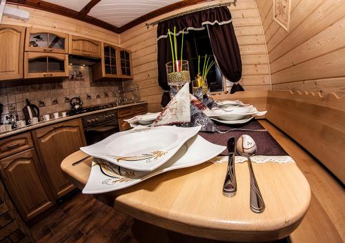 a kitchen with a wooden table with utensils on it at Chatka Pod Laskiem - Domki w górach in Soblówka