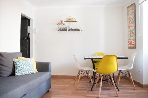 uma sala de estar com um sofá, uma mesa e cadeiras em Casa da Espera em Lisboa