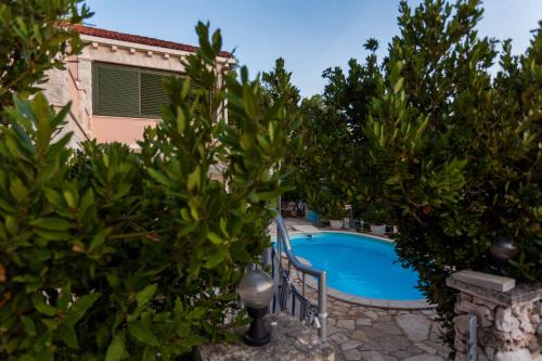una piscina rodeada de árboles y una casa en Villa Rosada, en Vela Luka