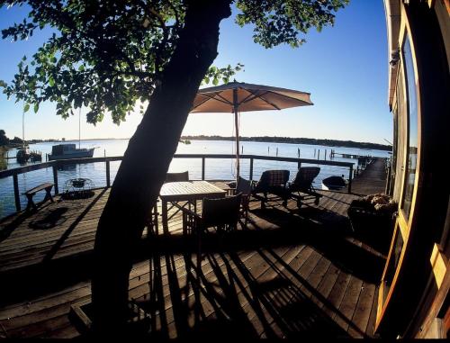 a deck with a table and chairs and an umbrella at Boathouse - Birks River Retreat in Goolwa