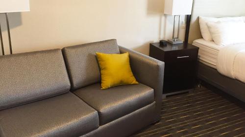 a couch with a yellow pillow in a hotel room at Comfort Inn & Suites Tigard near Washington Square in Tigard